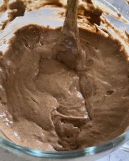 Una ciotola di glassa al cioccolato con un cucchiaio di legno dentro