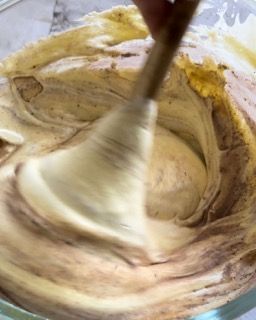 Una persona sta mescolando un impasto in una ciotola con un cucchiaio di legno.