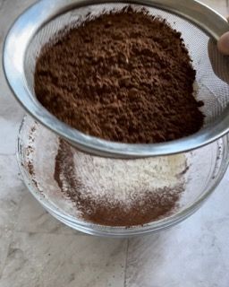 Una ciotola di cacao in polvere viene setacciata attraverso un colino
