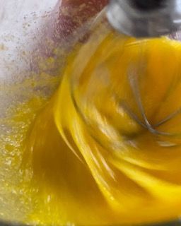 Primo piano di una persona che sbatte un liquido giallo in una ciotola.
