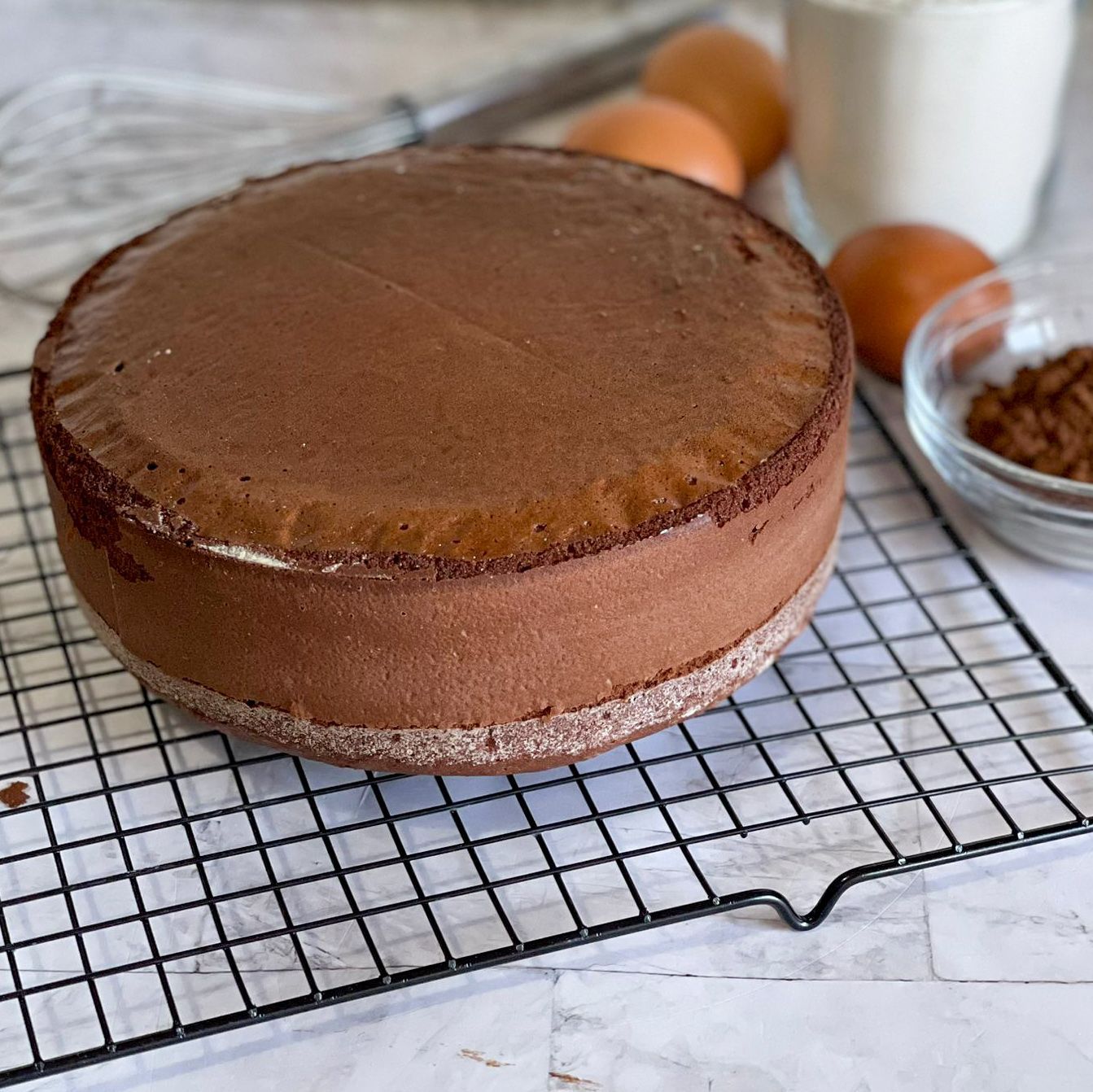 Una torta al cioccolato è appoggiata su una griglia di raffreddamento