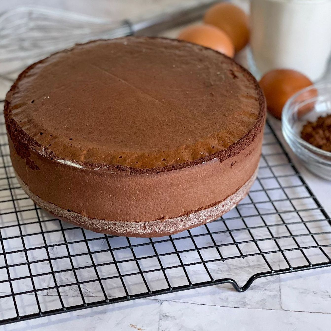 Una torta al cioccolato è appoggiata su una griglia di raffreddamento