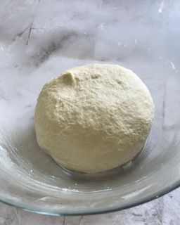 Una palla di pasta è posta in una ciotola di vetro.