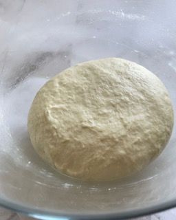 Una palla di pasta è posta in una ciotola di vetro.