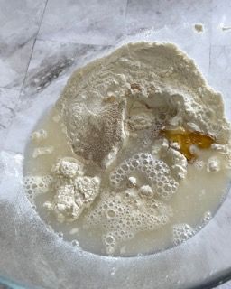 Primo piano di una ciotola di vetro piena di acqua e farina.