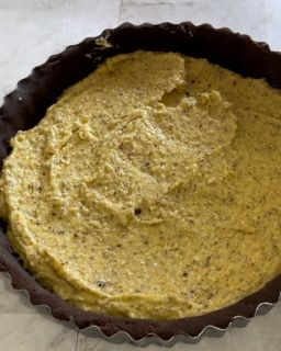 Una pasta per torta ripiena di salsa gialla è appoggiata su un tavolo.