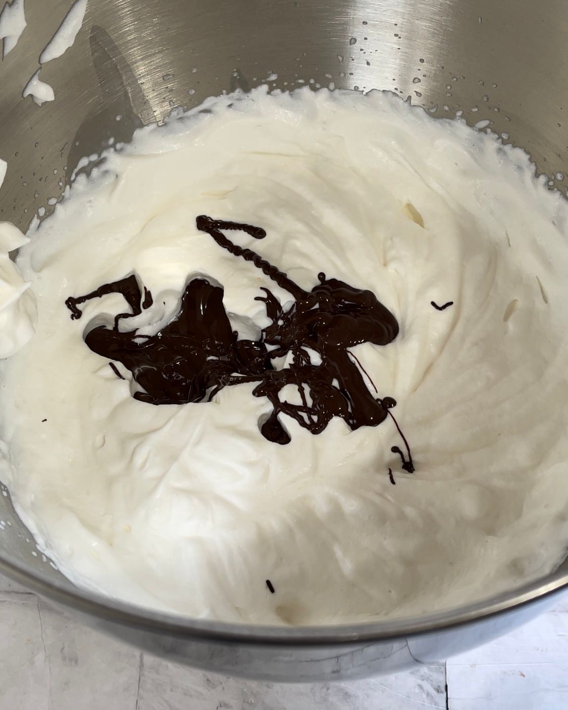 Una ciotola di panna montata con riccioli di cioccolato sopra.