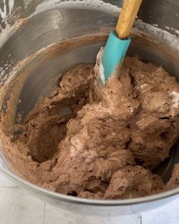 Una ciotola di glassa al cioccolato con una spatola dentro.