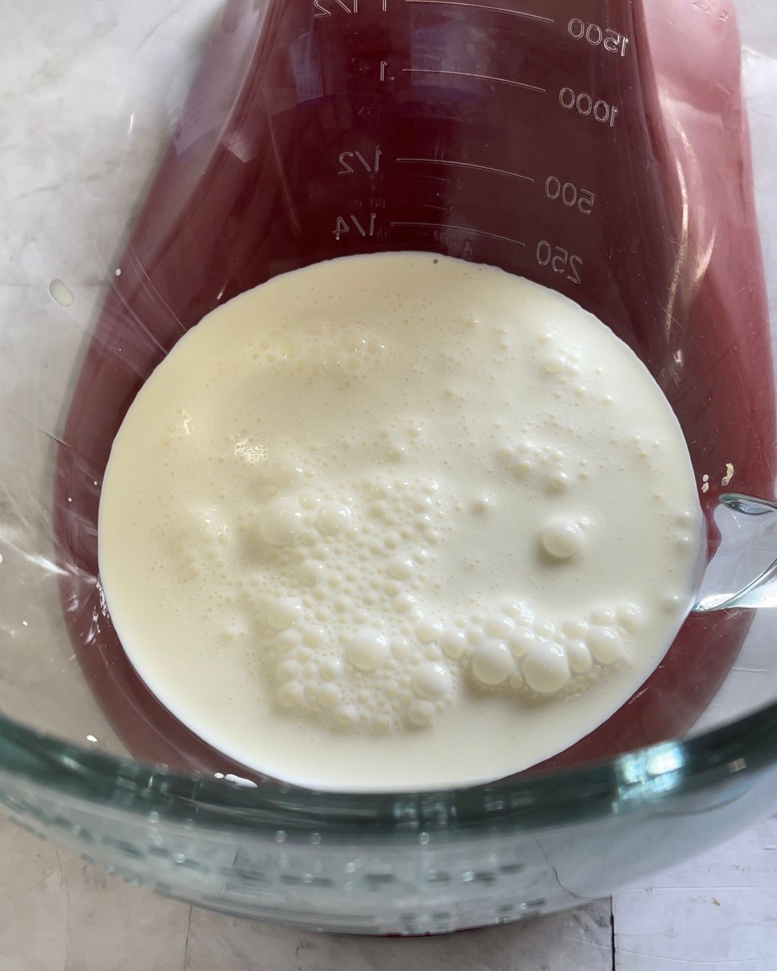 Un misurino di vetro riempito con un liquido bianco.