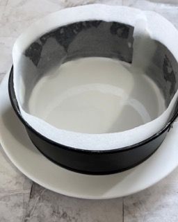 Una ciotola bianca con il bordo nero è appoggiata su un piatto bianco.