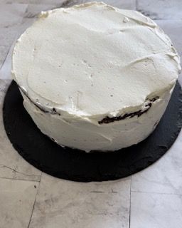 Una torta con glassa bianca è appoggiata su un piatto nero.