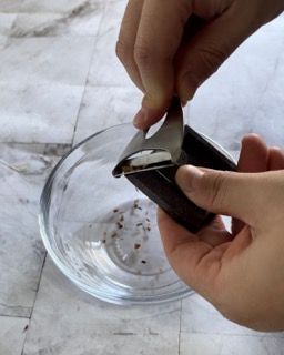 Una persona tiene in mano un pezzo di cioccolato sopra una ciotola di vetro