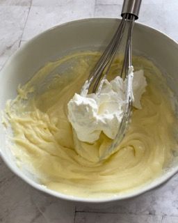 Una ciotola di panna montata con una frusta dentro.