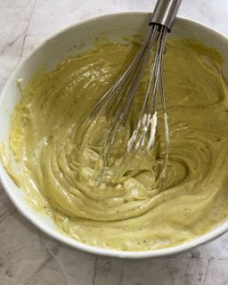 Una ciotola di salsa gialla con una frusta dentro.