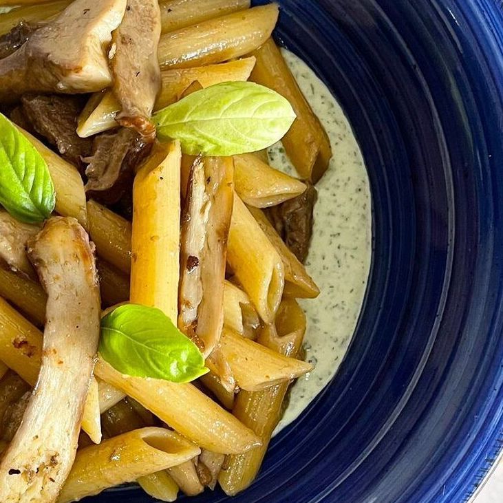 Un primo piano di una ciotola blu piena di pasta e salsa