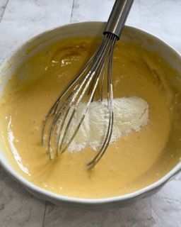 Una ciotola di pastella con una frusta dentro.