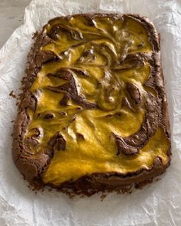 Un brownie con glassa gialla è appoggiato su un pezzo di carta oleata.