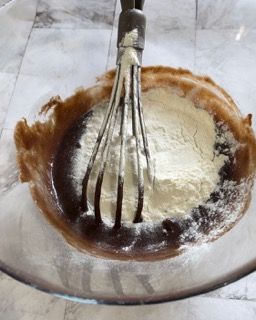 Una frusta è in una ciotola di cioccolato e farina