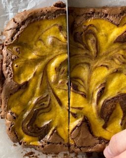 Una persona sta tagliando un brownie con glassa gialla