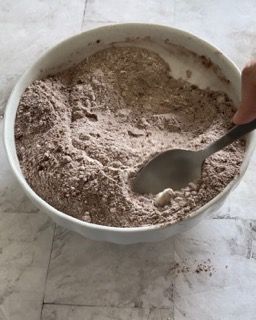 Una persona sta mescolando una ciotola di polvere marrone con un cucchiaio.