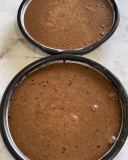 Due teglie piene di impasto al cioccolato sono appoggiate su un tavolo.