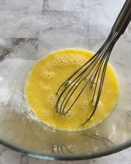 Una frusta è in una ciotola di liquido giallo.