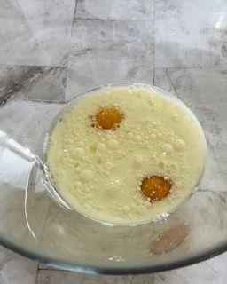 Primo piano di una ciotola piena di liquido con due uova dentro.