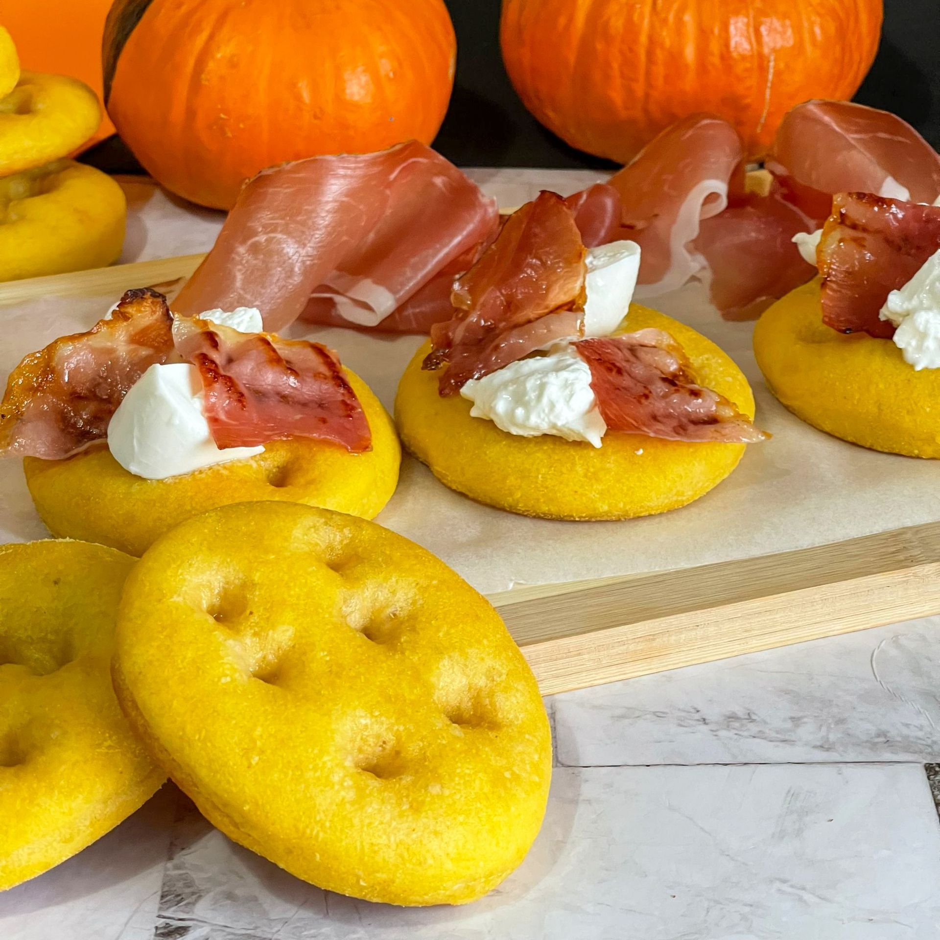 Un vassoio di cibo con patatine fritte e bacon su un tavolo con delle zucche sullo sfondo.