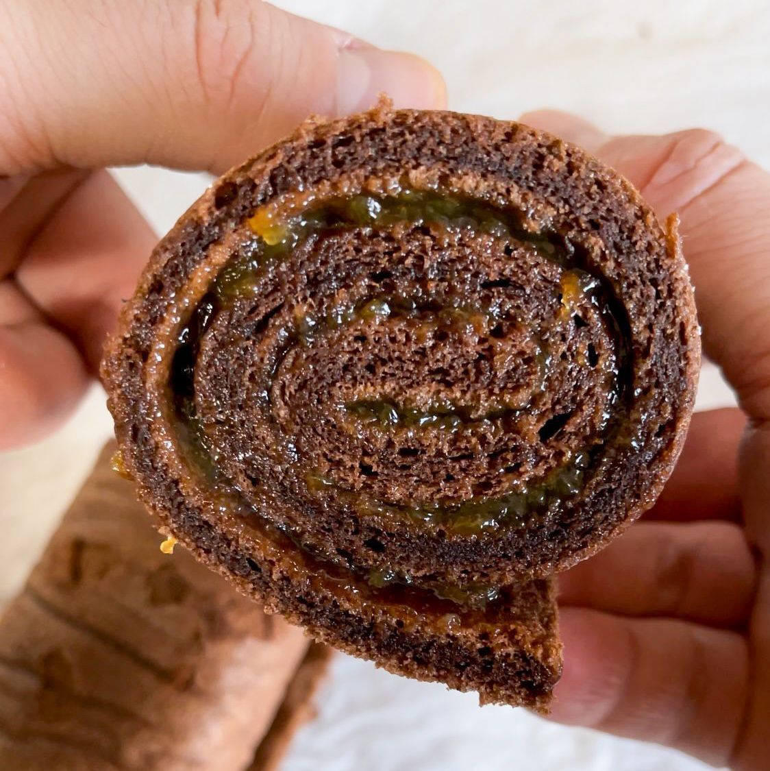 Una persona tiene in mano un pezzo di torta al cioccolato con un morso staccato