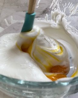 Una ciotola di panna montata con un cucchiaio di legno dentro