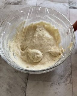 Una ciotola di pastella è coperta da pellicola trasparente su un tavolo.
