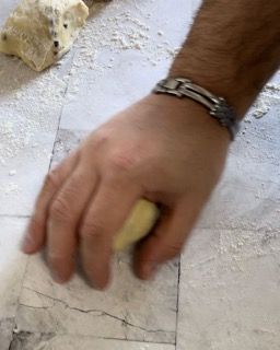 Una persona tiene in mano una palla di pasta.