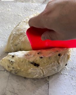 Una persona tiene una spatola rossa sopra un pezzo di impasto.