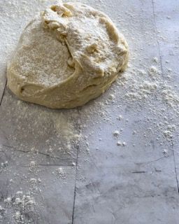 Una palla di pasta è appoggiata su un tavolo ricoperto di farina.