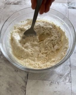 Una persona sta mescolando una ciotola di farina con una forchetta.