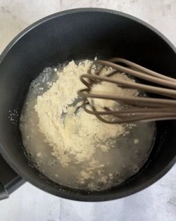 Si usa una frusta per mescolare gli ingredienti in una pentola piena di liquido.