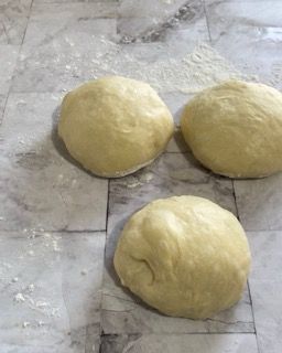 Tre palline di pasta sono appoggiate su una superficie di marmo.