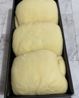 Tre pagnotte di pane sono in una padella su un tavolo.
