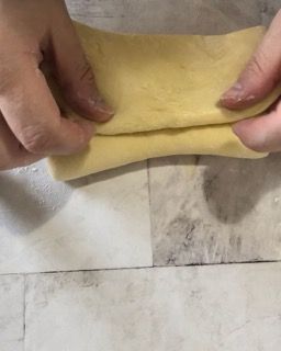 Una persona sta stendendo un pezzo di pasta su un tavolo.