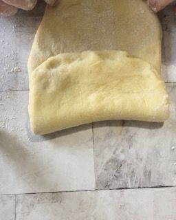 Una persona sta stendendo un pezzo di pasta su un tavolo.