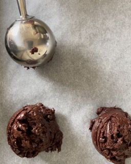 Due palline di gelato al cioccolato accanto a un cucchiaio