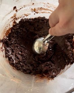 Una persona sta usando un cucchiaio di gelato in una ciotola di salsa al cioccolato