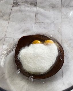 Primo piano di una ciotola di uova e zucchero su un tavolo.