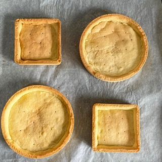 Quattro croste di torta sono appoggiate su un pezzo di carta oleata
