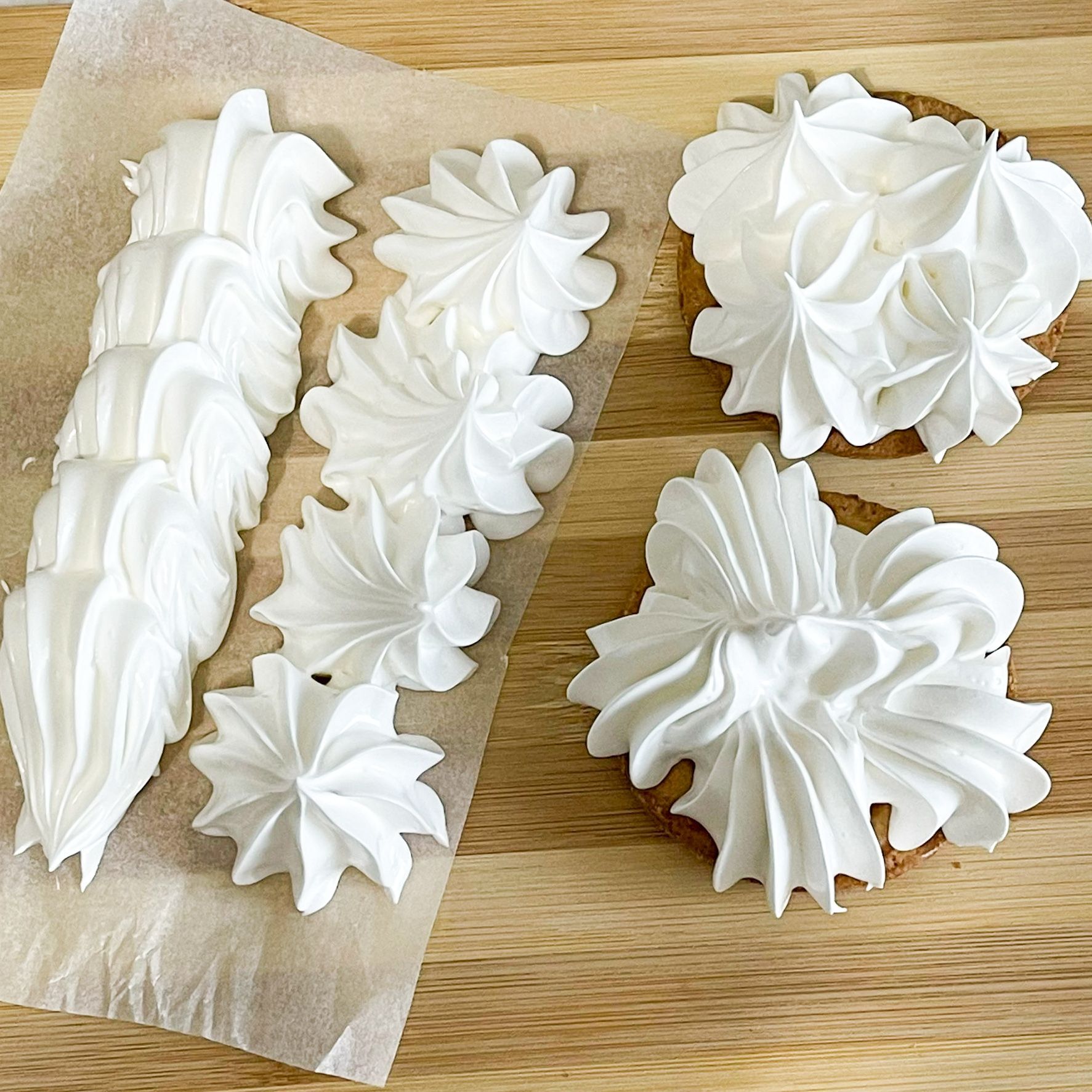 Tre cupcakes decorati con glassa bianca su un tavolo di legno.