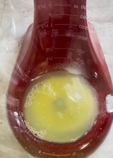Un misurino rosso riempito con un liquido giallo.