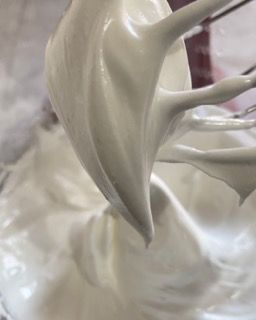Primo piano di una frusta in una ciotola di panna montata.