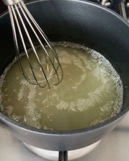 Una frusta è in una pentola con del liquido sul fornello.