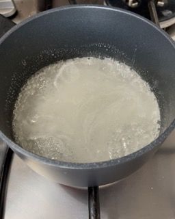 Una pentola piena di liquido è posta sopra un fornello.