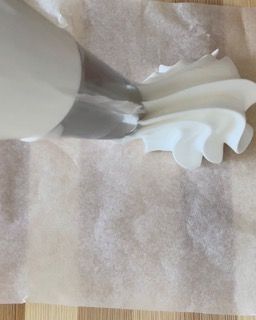 Una persona sta montando la panna su un pezzo di carta oleata.